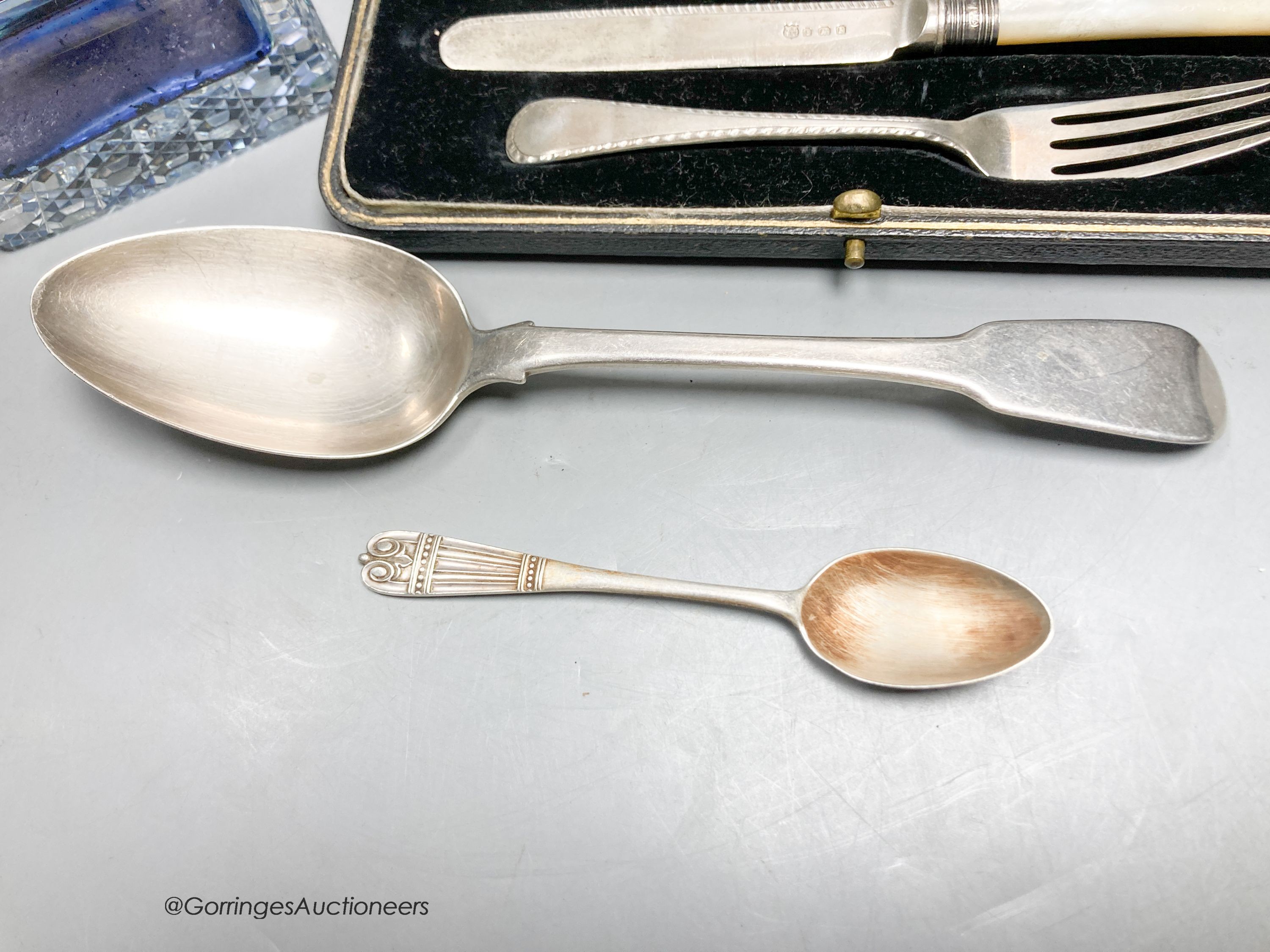 A silver mounted glass inkwell, two silver spoons and a silver Christening set.